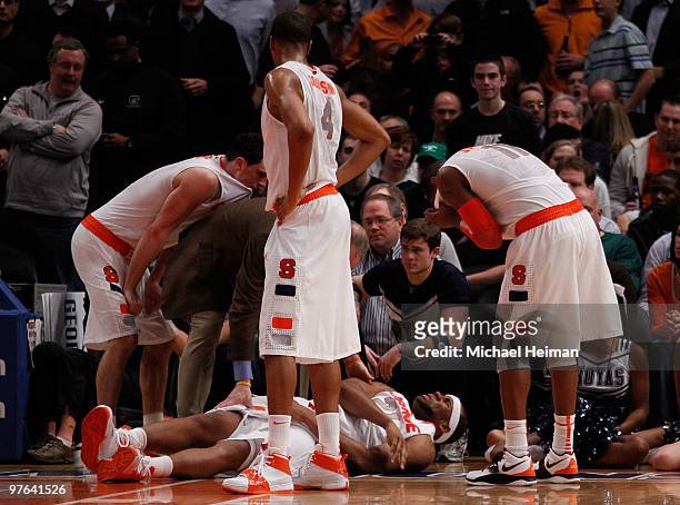Arinze Onuaku of the Syracuse Orange lays on the floor after being injured as teammates Andy Rautins, Wes Johnson and Scoop Jardine look on against...