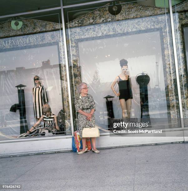 New York City - View of an unidentified woman with several shopping bags as she stands in front of a department store window in Queens, New York.