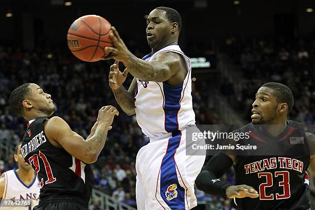 Sherron Collins of the Kansas Jayhawks passes the ball between John Roberson and Nick Okorie of the Texas Tech Red Raiders in the second half during...