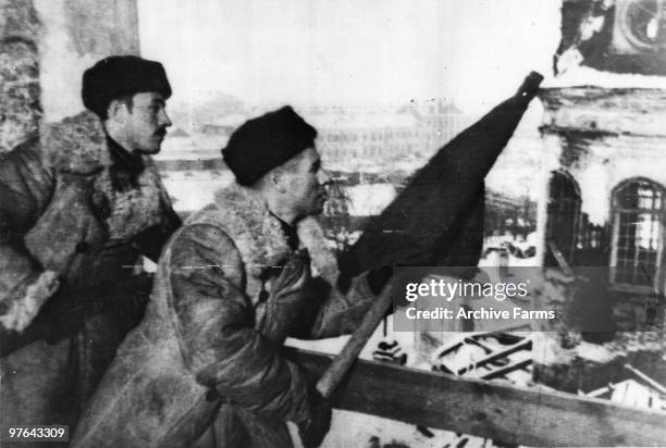 The red banner of the Soviet Army is hoisted up in a recaptured part of Stalingrad, as the German Sixth Army is beaten, 1943.