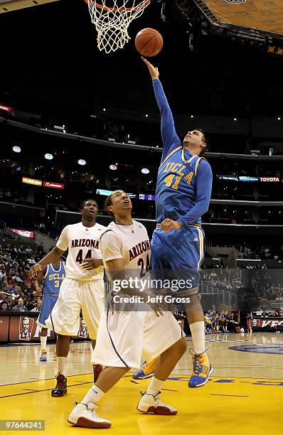 Nikola Dragovic of the UCLA Bruins drives to the basket over Brendon Lavender of the Arizona Wildcats in the first half during the Quarterfinals of...