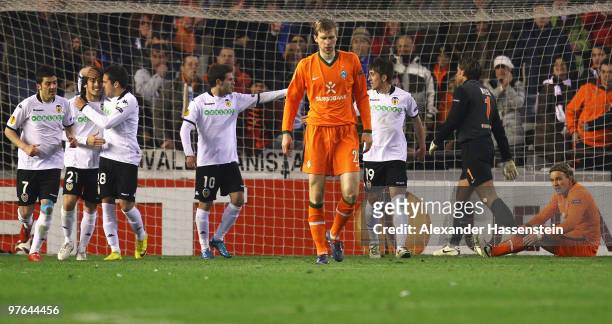 Per Mertesacker of Bremen and his team mate Clemens Fritz looks on whilst Juan Mata of Valencia celebrates his first team goal with his team mates...