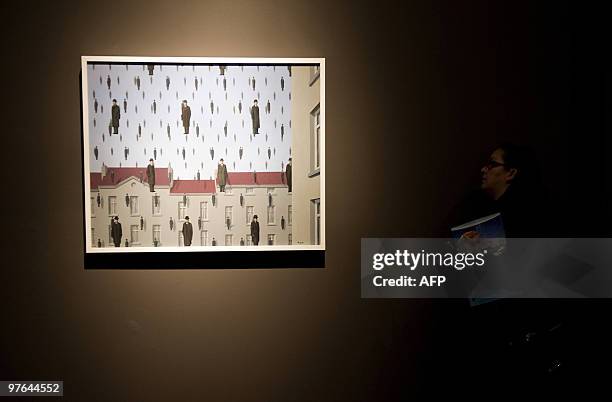 Visitor looks at "Golconda 1953" by the Belgian artiste Rene Magritte exhibited during a press conference at the Fine Arts Palace in Mexico City on...