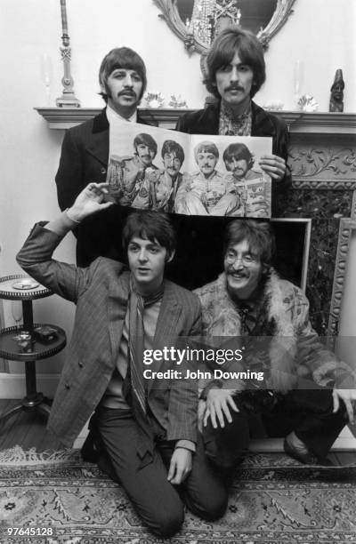 British pop group The Beatles (clockwise from top left: Ringo Starr, George Harrison , John Lennon and Paul McCartney pose with the cover of their...