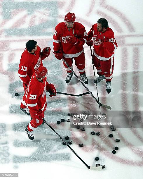 Drew Miller of the Detroit Red Wings and teammates Pavel Datsyuk, Darren Helm and Henrik Zetterberg have a quick conversation on the ice during...