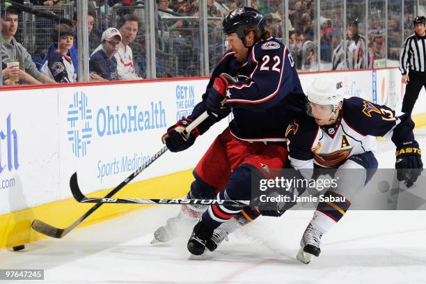 Mike Commodore of the Columbus Blue Jackets attempts to keep Vyacheslav Kozlov of the Atlanta Thrashers away from the puck during the first period on...