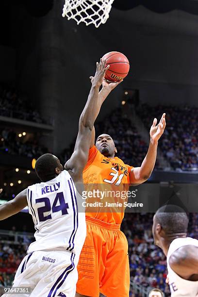 Matt Pilgrim of the Oklahoma State Cowboys shoots a shot in the lane over Curtis Kelly of the Kansas State Wildcats in the first half during the...