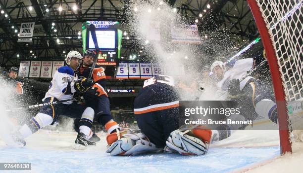 Patrik Berglund of the St. Louis Blues is tripped up and sprays ice on Martin Biron of the New York Islanders at the Nassau Coliseum on March 11,...