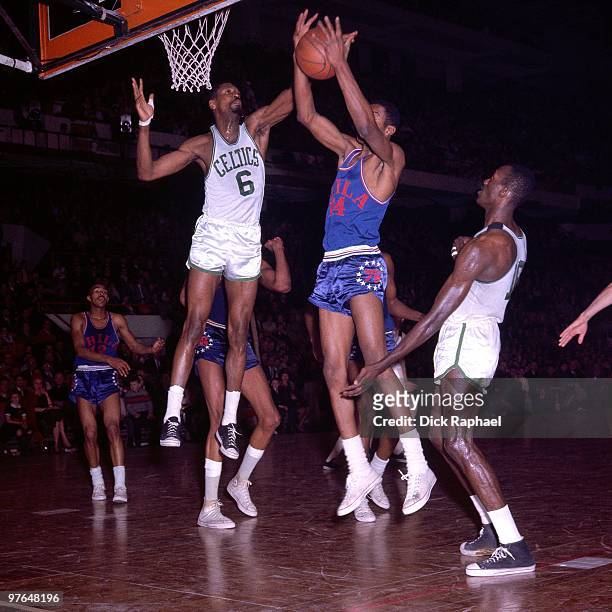 Bill Russell of the Boston Celtics blocks a shot attempt by Ben Warley of the Philadelphia 76ers during a game played in 1965 at the Boston Garden in...