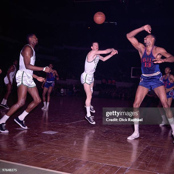 John Havlicek of the Boston Celtics passes against Wilt Chamberlain of the Philadelphia 76ers during a game played in 1965 at the Boston Garden in...