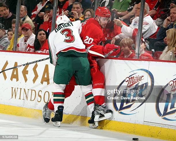 Marek Zidlicky of the Minnesota Wild checks Drew Miller of the Detroit Red Wings into the sideboards during an NHL game at Joe Louis Arena on March...