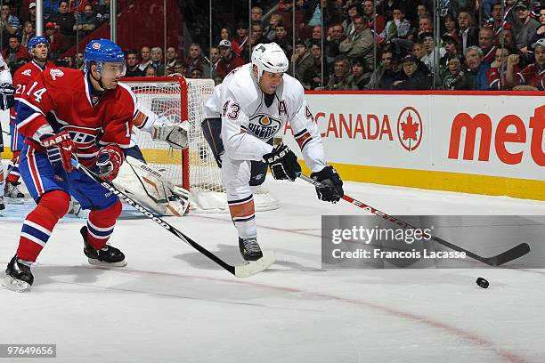 Jason Strudwick of Edmonton Oilers clears the puck in front of Tomas Plekanec of Montreal Canadiens during the NHL game on March 11, 2010 at the Bell...