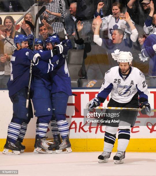 Luke Schenn, Phil Kessel and Tyler Bozak of the Toronto Maple Leafs celebrate the teams win as Martin St. Louis of the Tampa Bay Lightning skates...