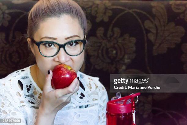 lady eating a royal gala apple with a reusable water container on the table - gala apple stock pictures, royalty-free photos & images