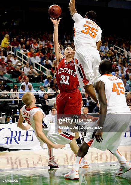 Dennis Horner of the NC State Wolfpack puts up a shot between Tanner Smith and Trevor Booker of the Clemson Tigers in their first round game in the...