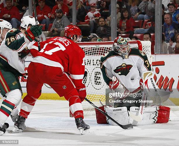 Josh Harding of the Minnesota Wild makes a save behind Patrick Eaves of the Detroit Red Wings on March 11, 2010 at Joe Louis Arena in Detroit,...