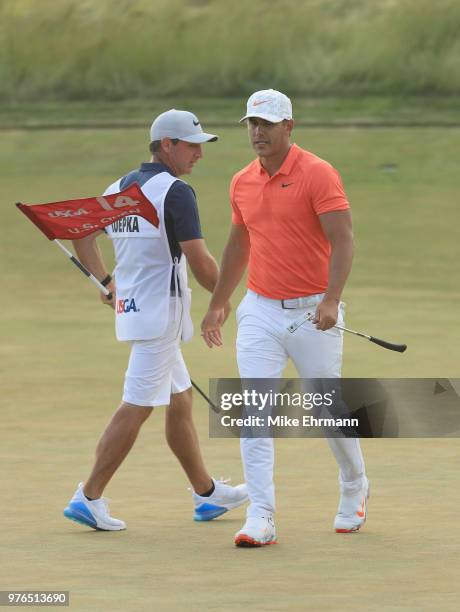 Brooks Koepka of the United States and caddie Richard Elliott walk on the 14th green during the third round of the 2018 U.S. Open at Shinnecock Hills...