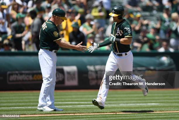 Chad Pinder of the Oakland Athletics is congratulated by third base coach Matt Williams after Pinder hit a solo home run against the Los Angeles...
