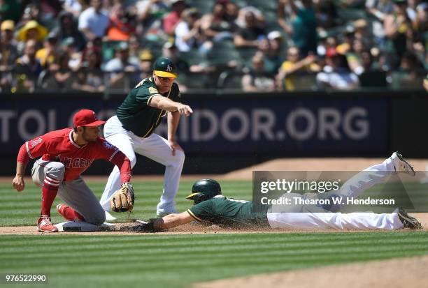 Chad Pinder of the Oakland Athletics dives into third base with a triple ahead of the throw to David Fletcher of the Los Angeles Angels of Anaheim as...