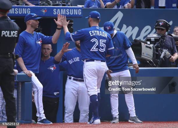 Marco Estrada of the Toronto Blue Jays is congratulated by J.A. Happ and teammates on the top step of the dugout as he comes out of the game in the...