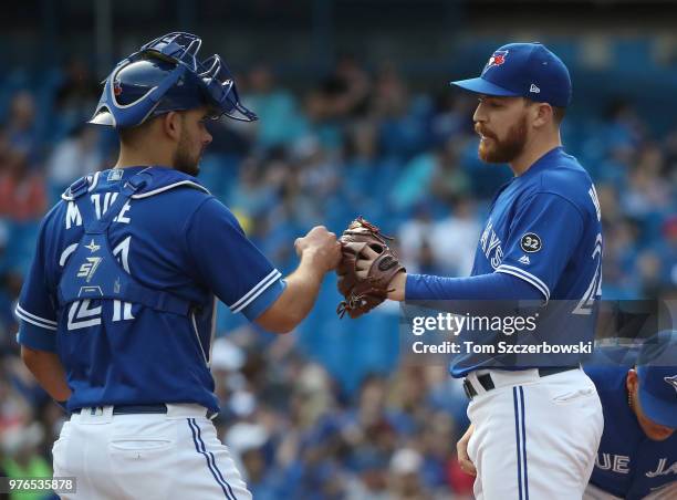 Danny Barnes of the Toronto Blue Jays is congratulated by Luke Maile moments before being relieved after retiring both batters he faced in the eighth...