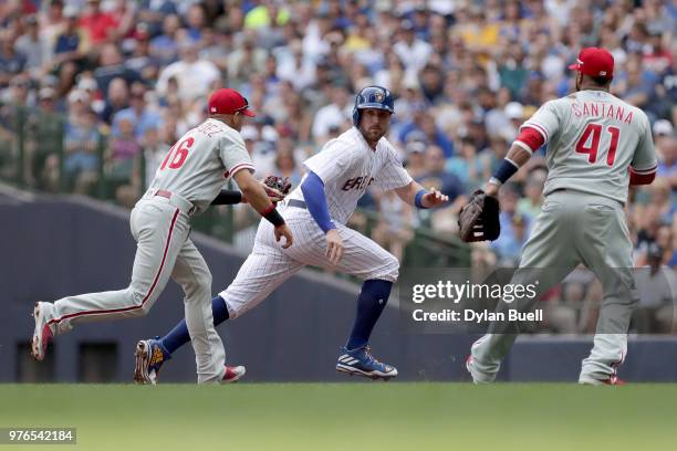 Travis Shaw of the Milwaukee Brewers gets caught in a run-down between Cesar Hernandez and Carlos Santana of the Philadelphia Phillies in the first...
