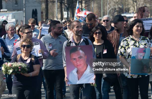 April 2018, Germany, Berlin: People walking through Britz holding photos of Burak.B on their way to the unveiling of a memorial. The young man was...