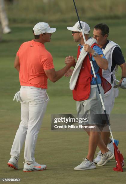 Brooks Koepka of the United States shakes hands with caddies James Walton and Richard Elliott on the 18th green during the third round of the 2018...
