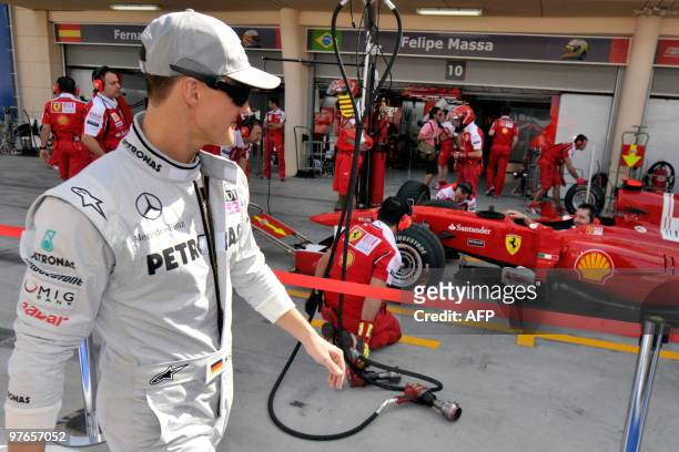 Mercedes GP's German driver Michael Schumacher walks past his former team Ferrari in the pits of the Bahrain international circuit on March 12, 2010...