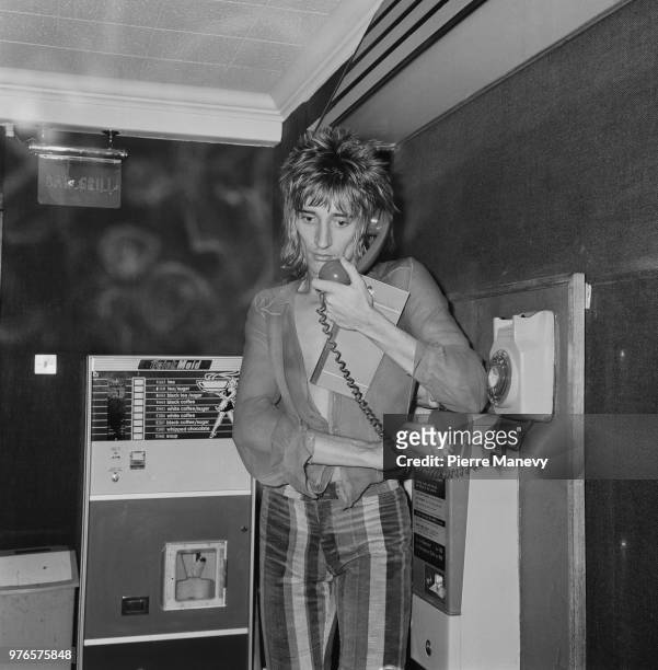 British rock singer and songwriter Rod Stewart pictures while making a phone call, UK, 8th November 1973.