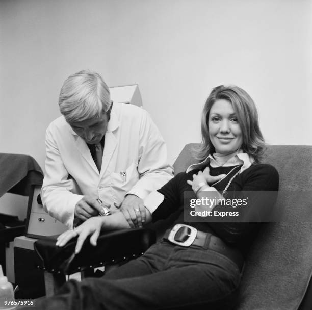 Australian actress Annette Andre being visited by Swindon Town FC physiotherapist Kevin Morris, UK, 15th October 1973.