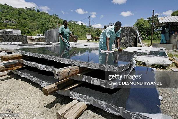 Workers polish slates of black granite stones at Zimbabwe's top black granite producer Natural Stone Export Company in Mutoko on February 8, 2010....