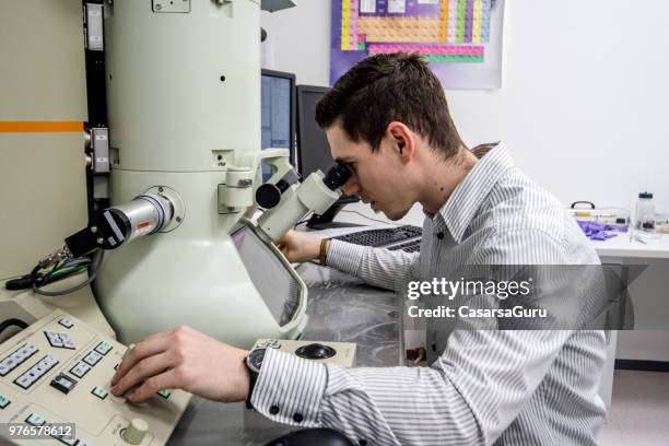 male scientist looking inro field emission electron microscope - electron microscope stock pictures, royalty-free photos & images