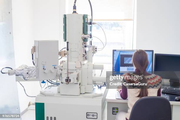 scienziata femminile che analizza i dati dal microscopio elettronico ad emissione di campo sul computer - microscopio elettronico a scansione foto e immagini stock