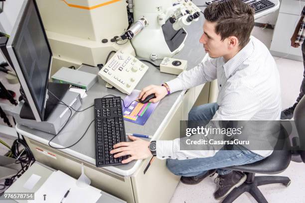 young man checking information from field emission electron microscope on computer - electron microscope micrographs stock pictures, royalty-free photos & images