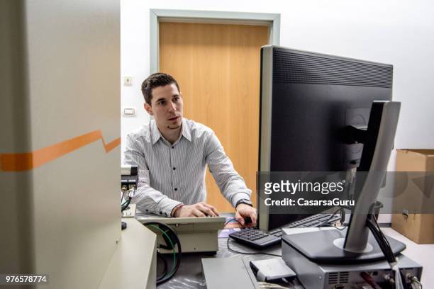 young scientist analyzing data from field emission electron microscope on computer screen - computer scientist stock pictures, royalty-free photos & images
