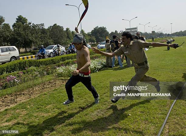 An Indian policeman attempts to detain a Tibetan in-exile demonstrating outside the Chinese embassy in New Delhi on March 12, 2010. Tibetans...