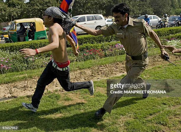 An Indian policeman grabs the bandana of a fleeing Tibetan in-exile demonstrating outside the Chinese embassy in New Delhi on March 12, 2010....