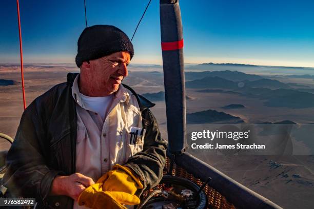 balloon pilot looks out from the basket over the sossusvlie area at dawn, namib desert, namib-naukluft, namibia (model release - strachan stockfoto's en -beelden