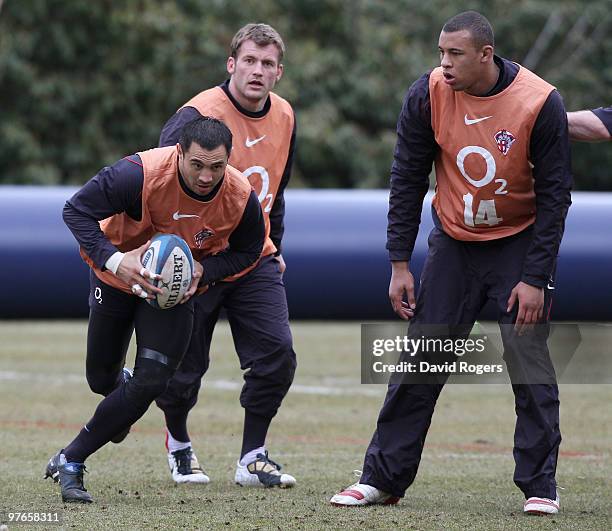 Riki Flutey runs with the ball with teammates Mark Cueto and Courtney Lawes in support during the England rugby union squad training session at...