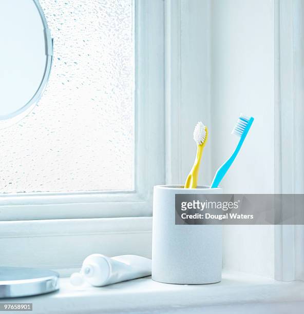 tooth brushes in cup sitting on bathrrom window - toothbrush ストックフォトと画像