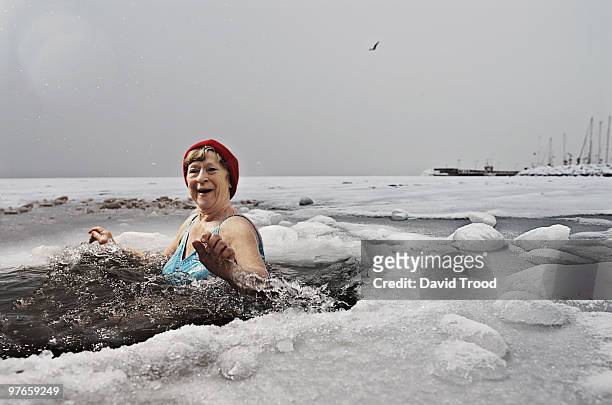 elderly woman bathing in the frozen sea. - david trood stock-fotos und bilder