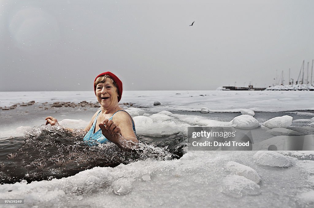 Elderly woman bathing in the frozen sea.