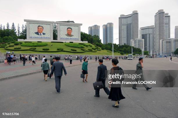 Groupe de gens passant devant des photos des leaders nord-coréens Kim Il-Sung et Kim Jong-Il à Pyongyang, en Corée du Nord, le 11 juin 2018.
