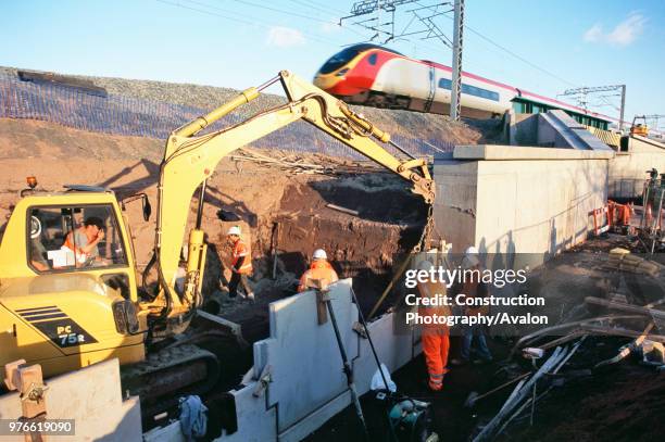 Fixing reinfroced earth facing panels for the bridge abutment - WCML as Virgin Train passes, Four bridges-Lichfield.
