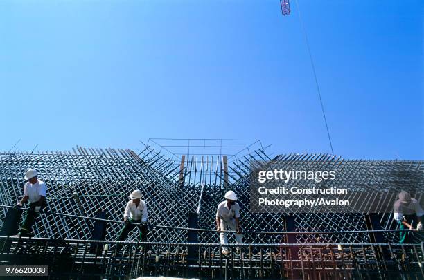 Construction site Four men manhandle a heavy bar for steel reinforcement at the top of a bridge pier on the Rion-Antirion bridge, Greece.