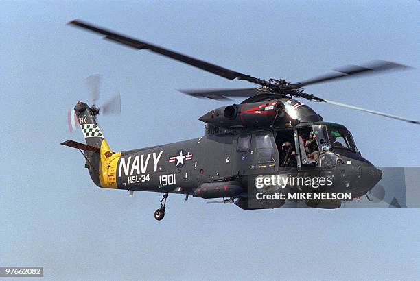 An armed crewman looks out of the door of a US Navy helicopter overflying the Gulf of Oman off Fujairah 21 July 1987. The copter warned off...