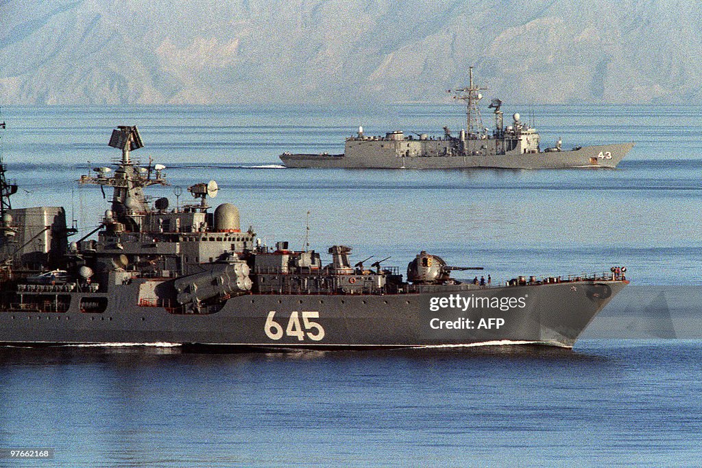 A Soviet warship (foreground) passes alo