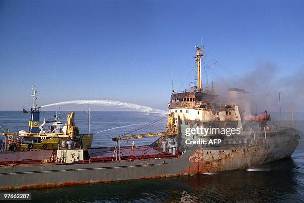 Tugboat puts out a fire November 23 on the 8,750 ton Romanian flagged freighter Fundulea which was hit by an Iranian warship, causing severe damage,...