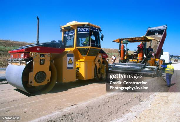 The base course or underlayer is placed by a paving machine and compacted for a new radial motorway link for Madrid in Spain.